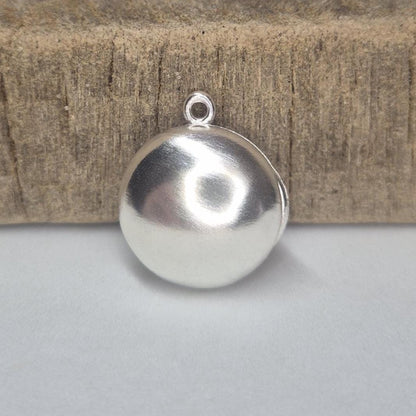 Closed Round Silver Locket Standing Against a Wooden Block.