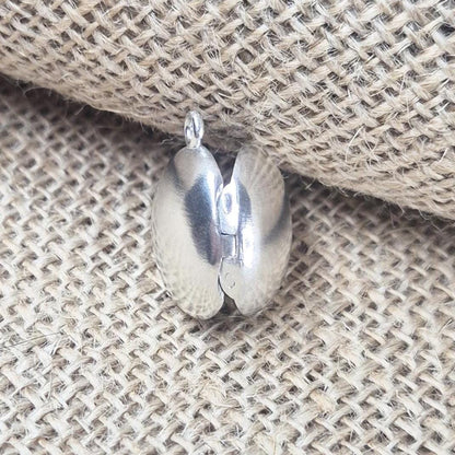 Rear View of an Open Round Silver Locket Against a Jute Background.