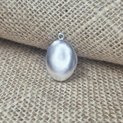 Closed Oval Silver Locket Against a Cloth Background.