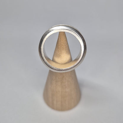 Straight-on view of a half channel ring balanced vertically on a cone, with the full circular band clearly framed.