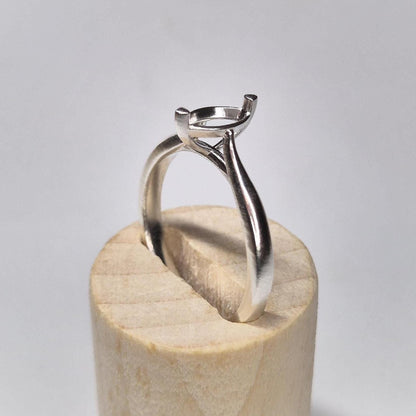 Side profile of a cathedral shank silver ring blank with a 2-prong marquise setting, displayed on a round wooden base.