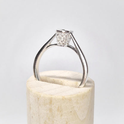 Side profile of a silver ring blank with an open basket bezel setting, displayed upright on a wooden base with a white background.