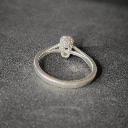 Silver ring blank with a cathedral shank and basket bezel setting for an emerald cut stone, shown from the rear on a dark background.