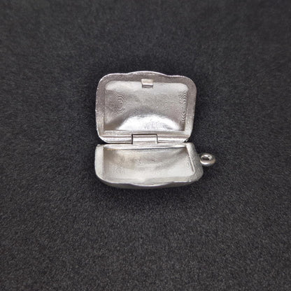 Sterling silver locket open flat on black background, clearly displaying both inner halves and hinge construction.