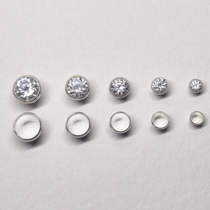 Lineup of sterling silver bezel settings from smallest to largest with mounted gemstones, including 4mm size.