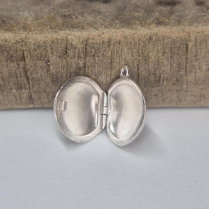 Standing Open Round Silver Locket Against a Wooden Block.
