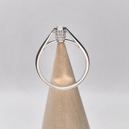 Side view of silver basket bezel ring displayed on a wood cone stand, with open cathedral-style shoulders and high-profile setting.