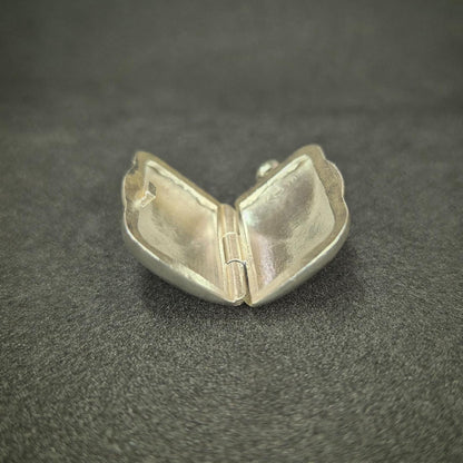 Open rectangular sterling silver locket photographed on a dark background, showing internal compartments and hinge detail.