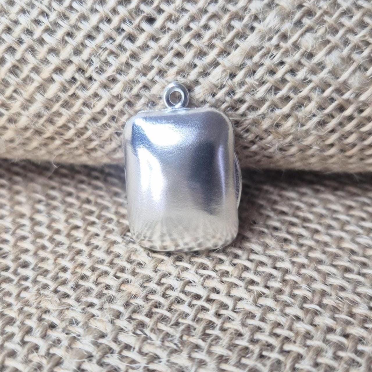 Sterling silver rectangular locket photographed on textured hessian fabric with soft natural lighting.