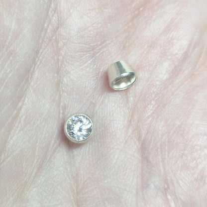 Sterling silver 4mm bezel cup and mounted gemstone shown on hand for size reference in custom jewellery making.