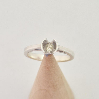 Top-down view of a silver ring blank with a central setting cup designed for a round gemstone.