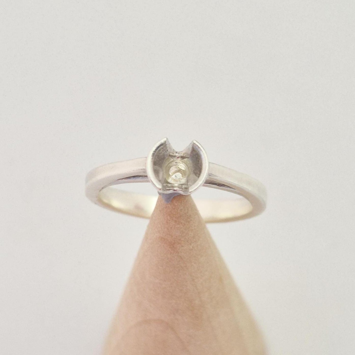 Top-down view of a silver ring blank with a central setting cup designed for a round gemstone.