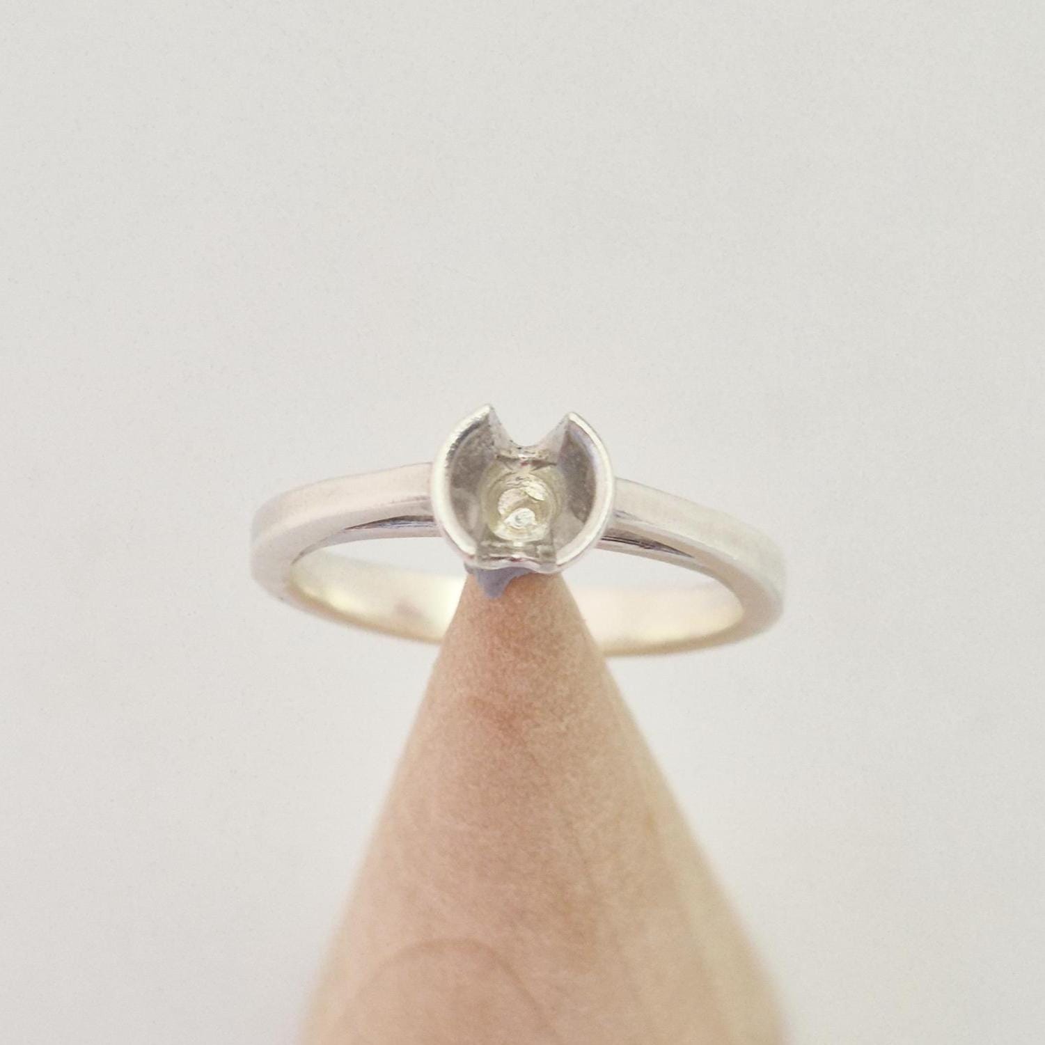 Top-down view of a silver ring blank with a central setting cup designed for a round gemstone.