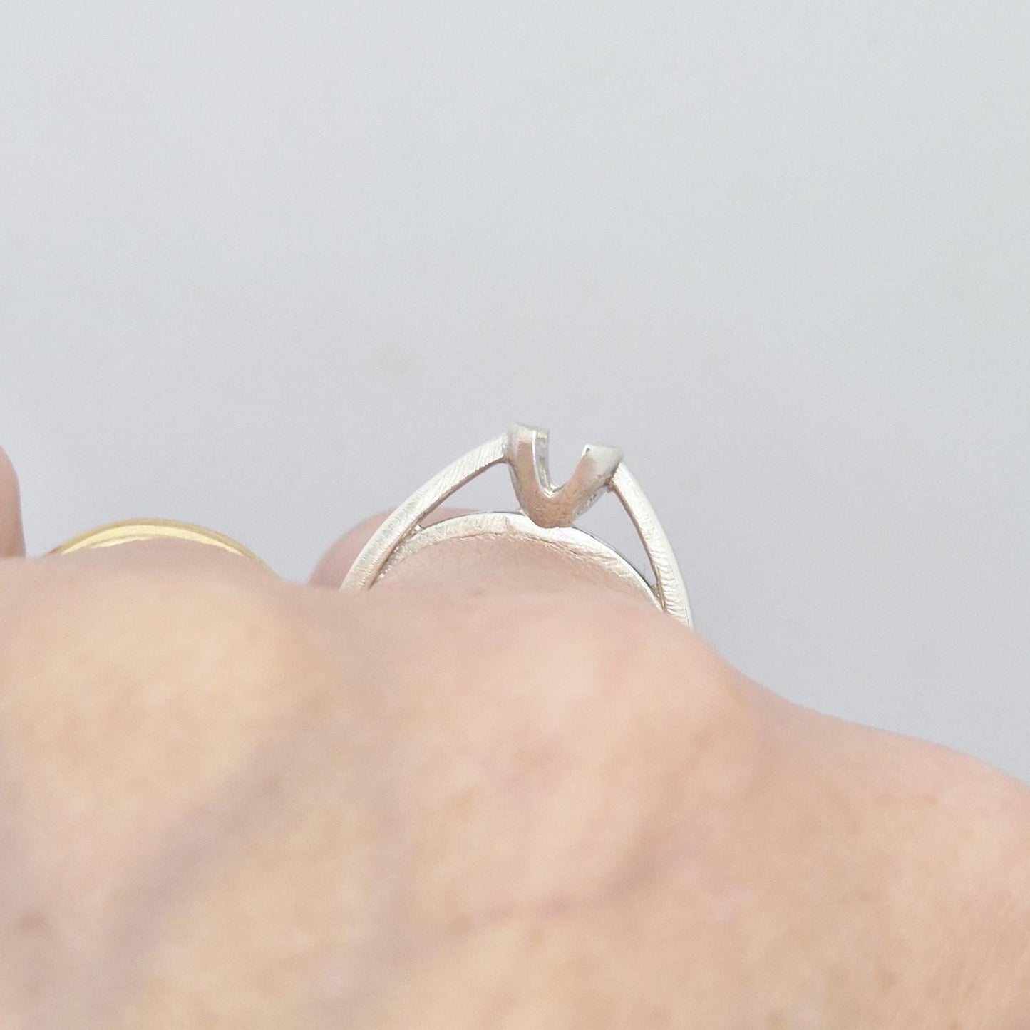 Close-up side view of the silver ring while worn, highlighting the open design and raised setting structure.