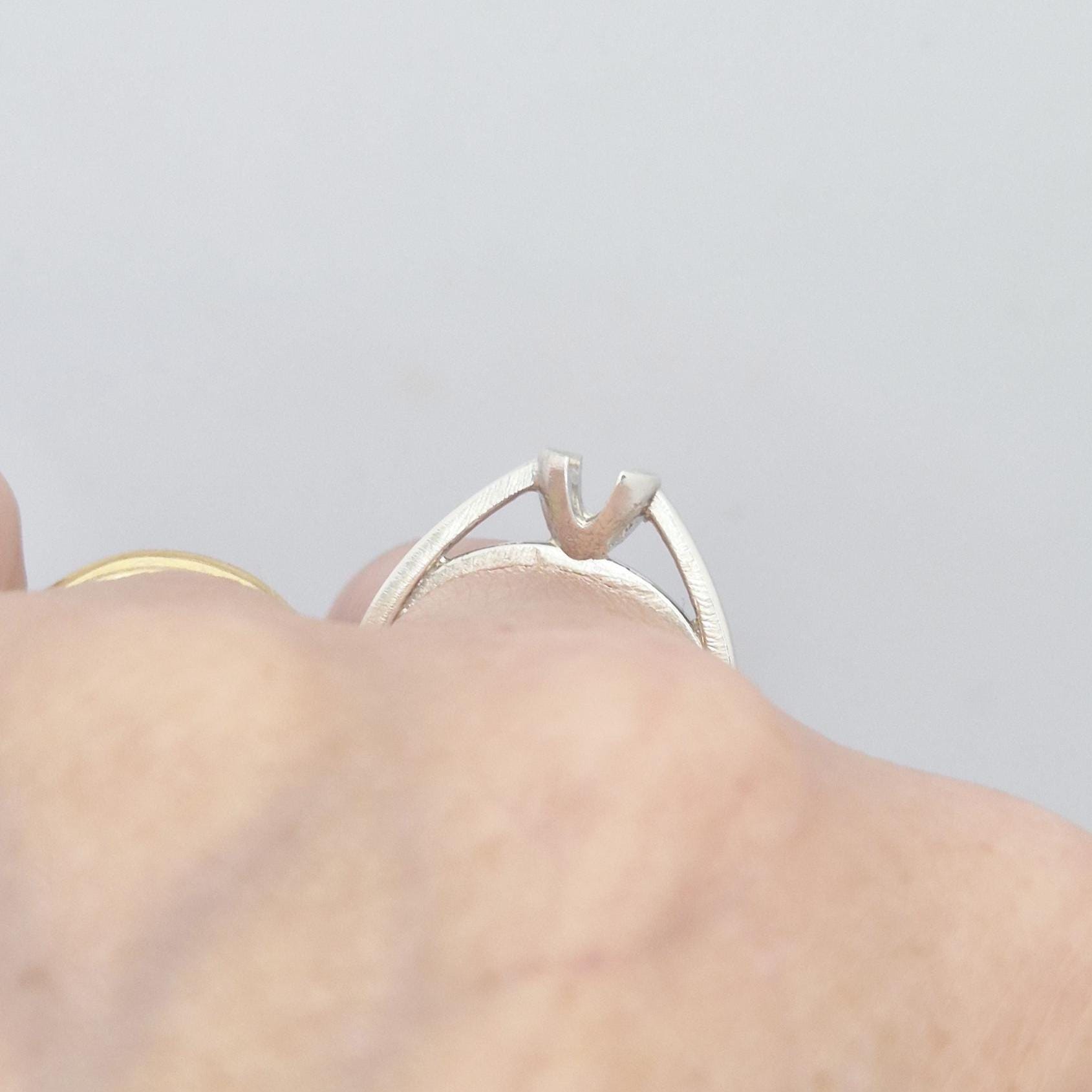 Close-up side view of the silver ring while worn, highlighting the open design and raised setting structure.