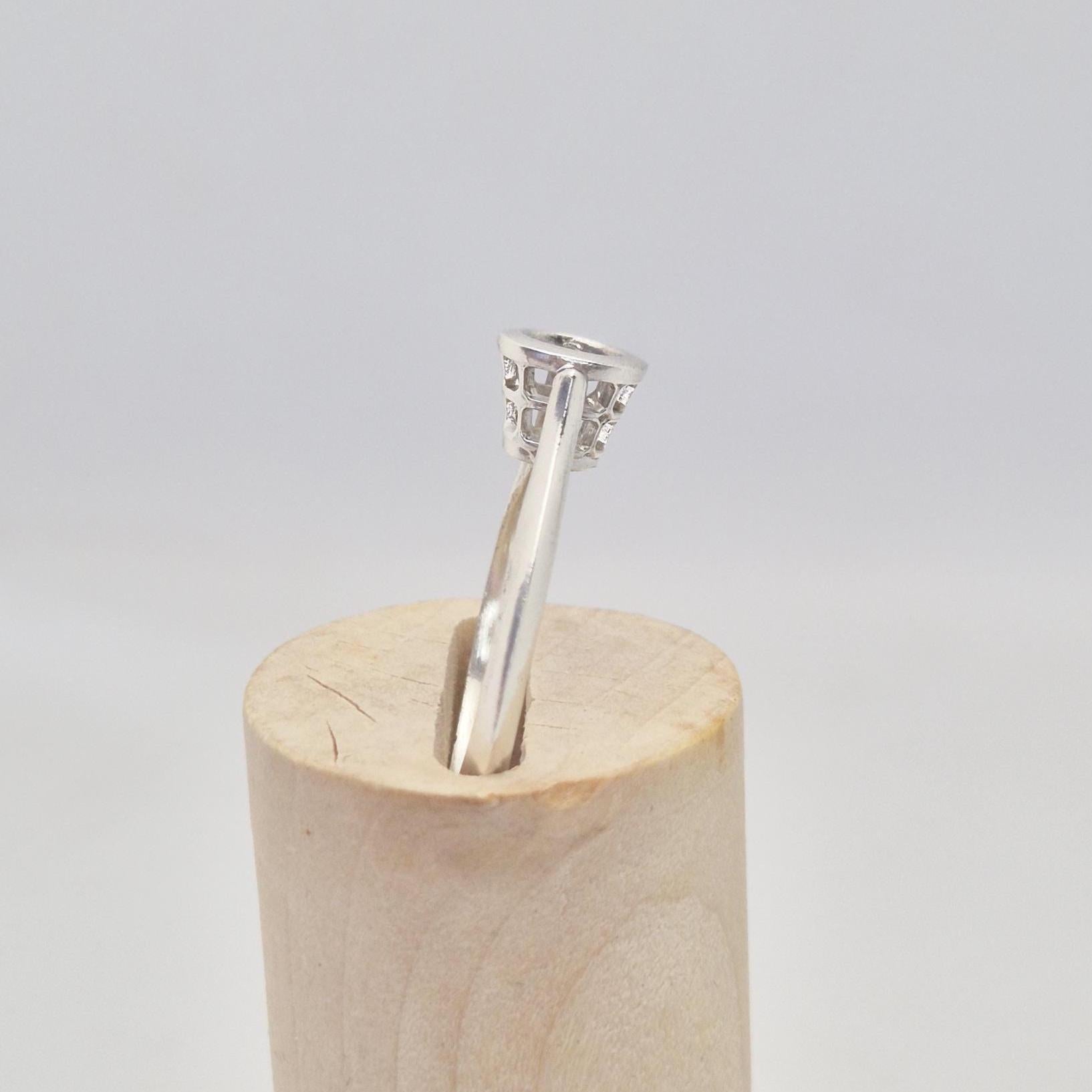 Side view of a silver ring setting with an empty round bezel, displayed upright on a light wooden cone. The ring band is smooth and tapers slightly towards the setting.