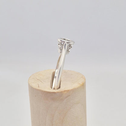 Side view of a silver ring setting with an empty round bezel, displayed upright on a light wooden cone. The ring band is smooth and tapers slightly towards the setting.