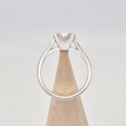 Back view of a sterling silver ring setting with a cushion cut bezel, displayed on a conical wooden stand, showing the full circle of the band and the back of the bezel.