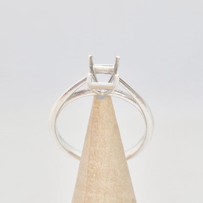 Silver cathedral setting princess cut ring blank on a conical wooden ring holder, viewed from the front, showing the empty four-prong setting and the band.