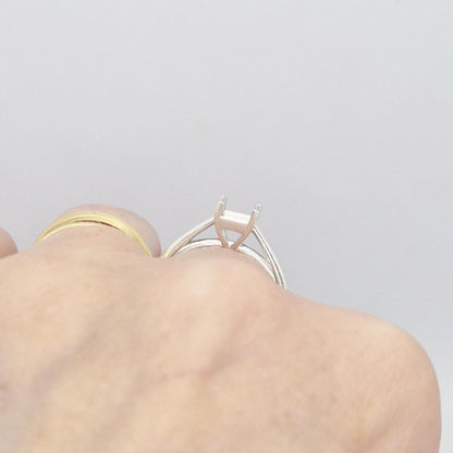 Close-up of a silver cathedral setting princess cut ring blank on a hand, showing the profile of the empty four-prong setting and the split shank band.