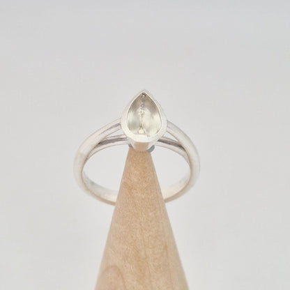 Silver pear cut bezel cathedral ring blank on a conical wooden ring holder, front view, showing the empty pear-shaped bezel setting.