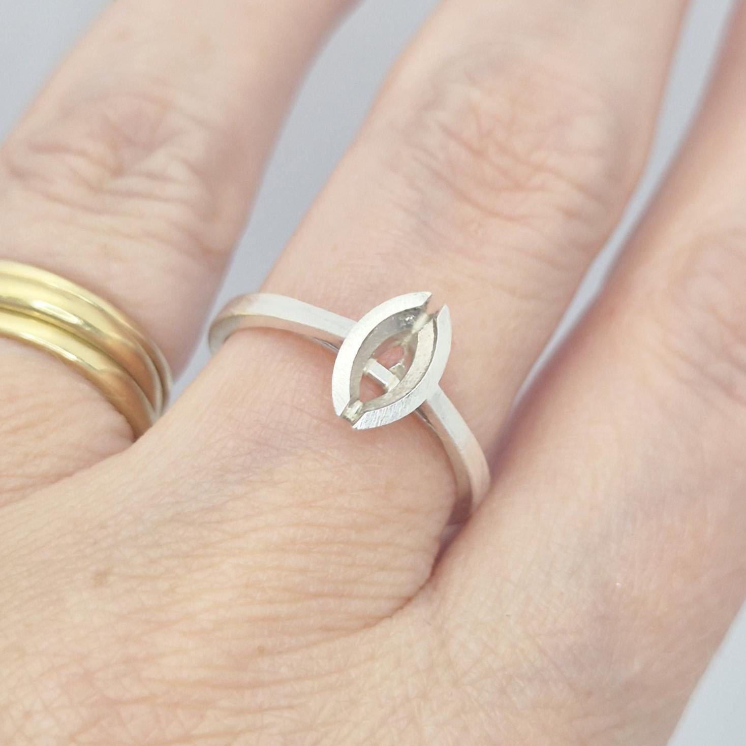 Silver marquise split bezel ring blank on a hand, next to a plain gold band, illustrating how the marquise setting sits on a finger.