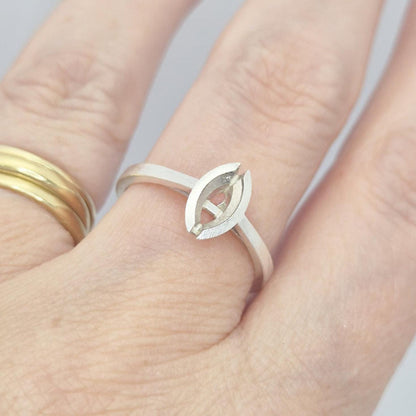 Silver marquise split bezel ring blank on a hand, next to a plain gold band, illustrating how the marquise setting sits on a finger.
