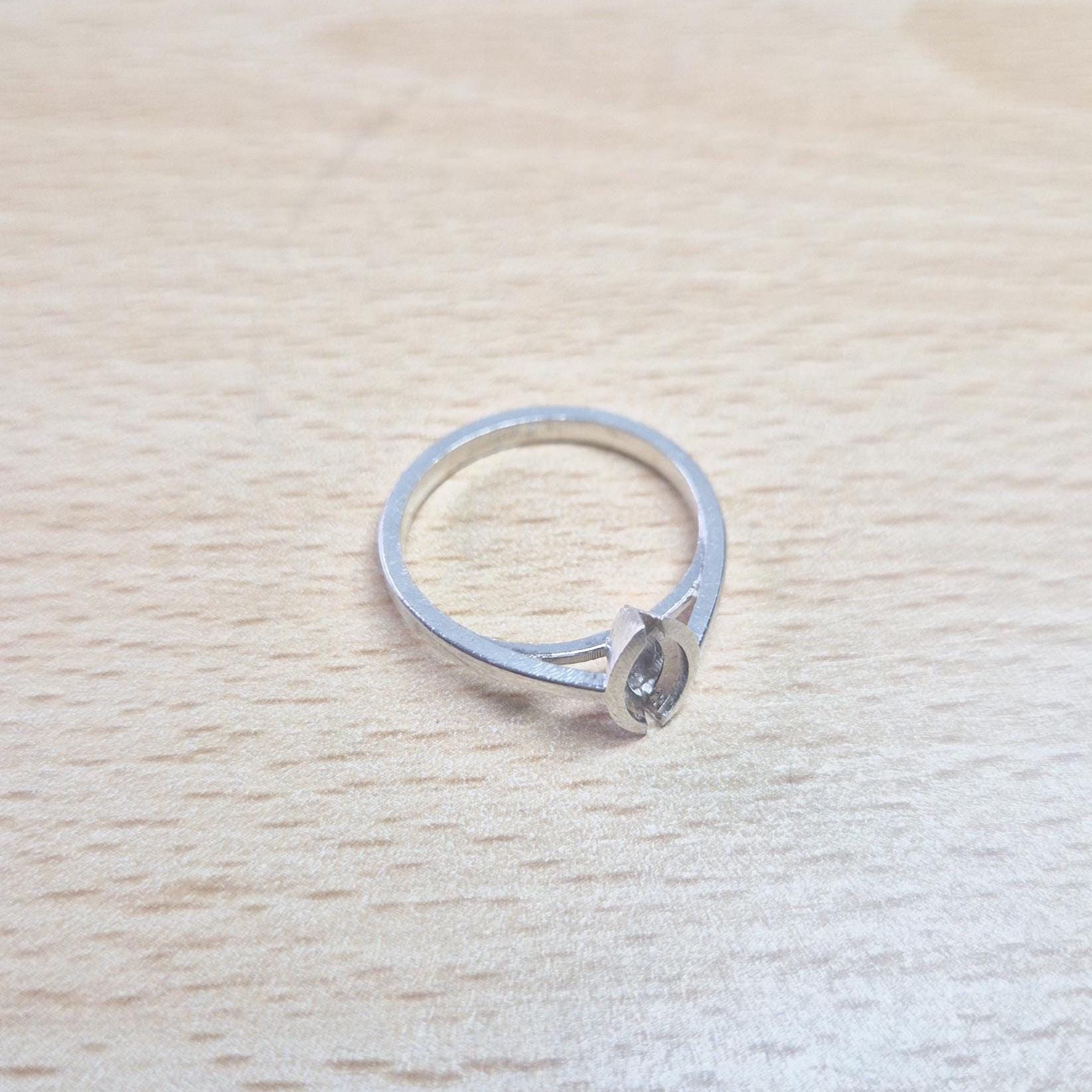 Silver marquise split bezel ring blank lying flat on a light wooden surface, viewed from above, showing the empty marquise-shaped split bezel and the entire ring.