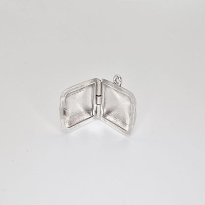 An open sterling silver square locket pendant, showcasing the hinge and the empty interior space of both sides, against a light grey background.