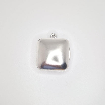 A direct overhead view of a closed sterling silver square locket pendant, showing its polished surface and the small top bail.
