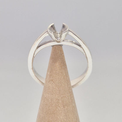 Front view of a silver solitaire ring setting with open V-shaped prongs, displayed on a wooden ring cone.