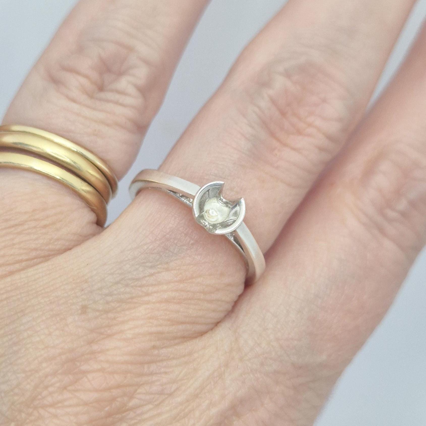 Silver solitaire ring worn on a finger, displaying the mounting and shank fit in a natural setting.