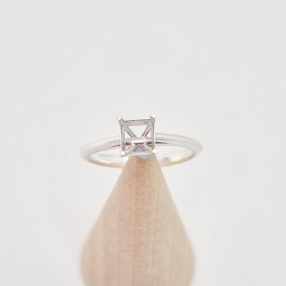 Silver cathedral setting princess cut ring blank on a conical wooden ring holder, viewed from the front, clearly showing the empty four-prong setting and the split shank design.