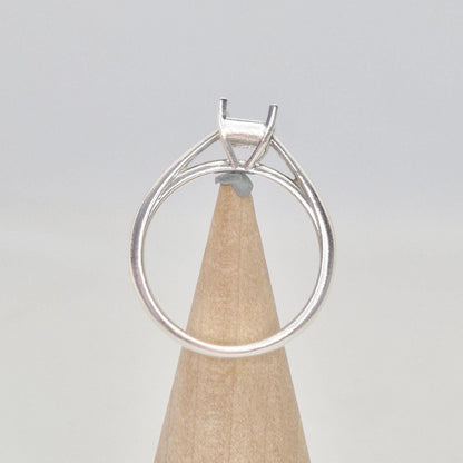 Silver cathedral setting princess cut ring blank on a conical wooden ring holder, viewed from the front, showing the empty four-prong setting and the band.