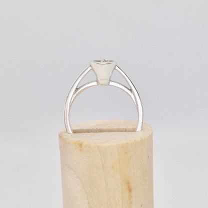 Silver pear cut bezel cathedral ring blank inserted into a cylindrical wooden ring holder, front view, with the empty pear-shaped bezel setting visible.