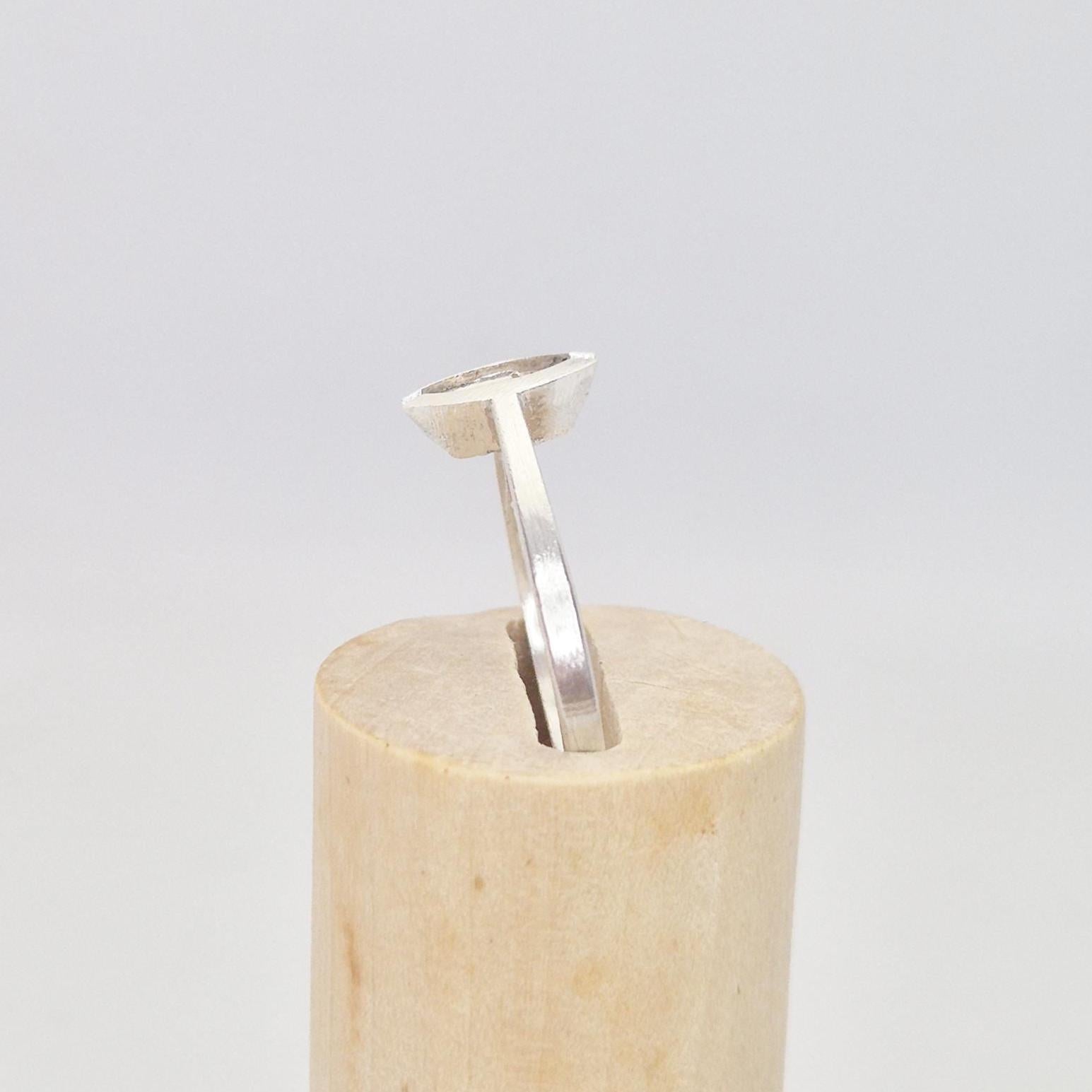 Side profile of a silver marquise split bezel ring blank inserted into a cylindrical wooden ring holder, showing the elevated empty marquise-shaped bezel.