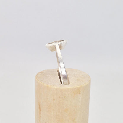 Side profile of a silver marquise split bezel ring blank inserted into a cylindrical wooden ring holder, showing the elevated empty marquise-shaped bezel.