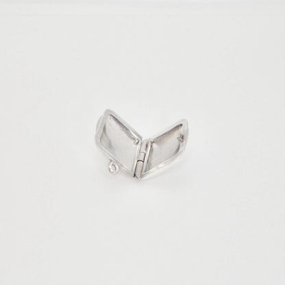 A blank sterling silver square locket pendant opened flat, revealing the two internal compartments and the small ring at the top for attachment, set against a plain white background.