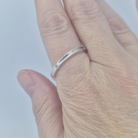 Very slim silver channel ring worn on the finger, demonstrating the understated profile and lightweight everyday fit.