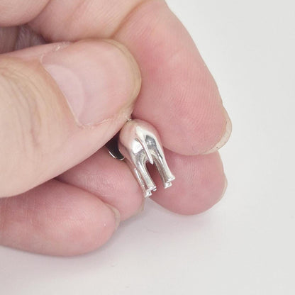 Close-up rear view of a silver elephant charm held between fingers, highlighting the tail and back leg detail.