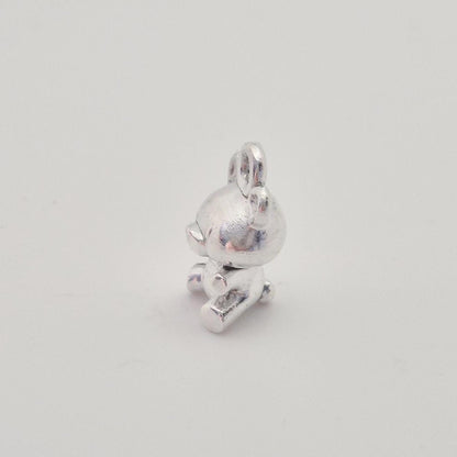 Side view of silver teddy bear charm showing bail loop and sculpted arms and legs