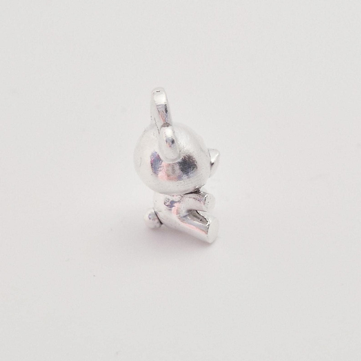 Angled view of silver teddy bear charm showing dimensional body and rounded detailing