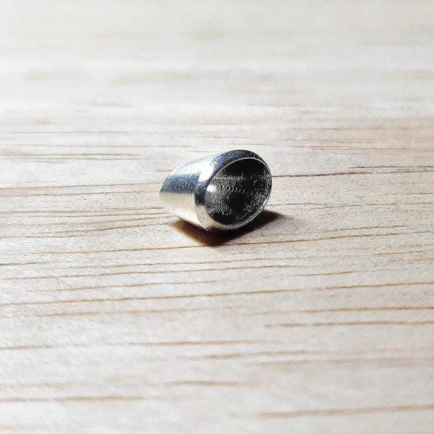 Small 6x4mm oval silver bezel viewed at a low angle, showing the polished rim and hollow interior for stone setting.