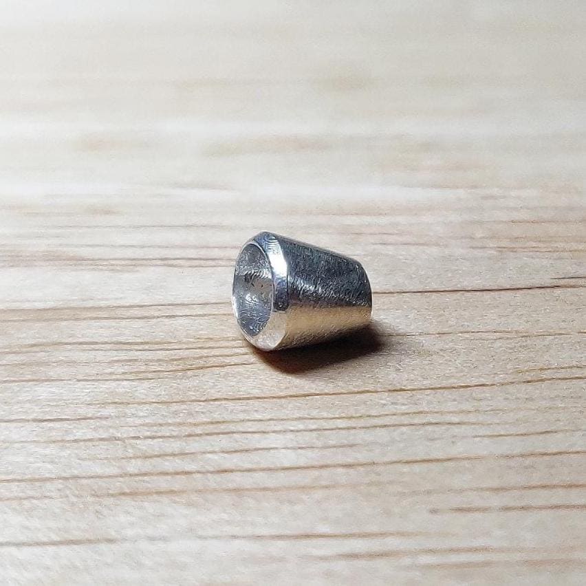 6x4mm oval silver bezel setting photographed from the side, displaying the smooth, slightly flared profile.