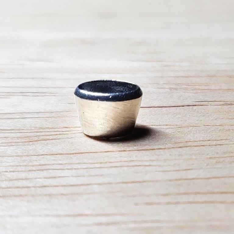 Polished 6x4mm oval silver bezel setting standing upright, showing the flat rim where a gemstone would be set.