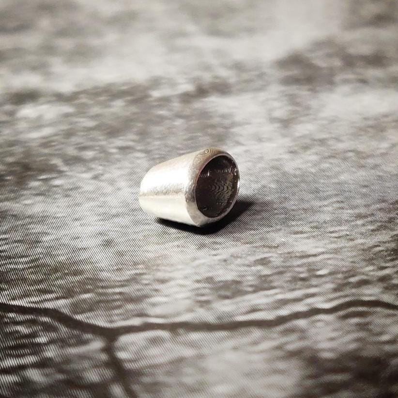 Upright 6x4mm oval silver bezel setting on a dark surface, showing the clean rim and inner seat for a faceted gem.