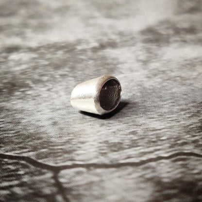 Upright 6x4mm oval silver bezel setting on a dark surface, showing the clean rim and inner seat for a faceted gem.