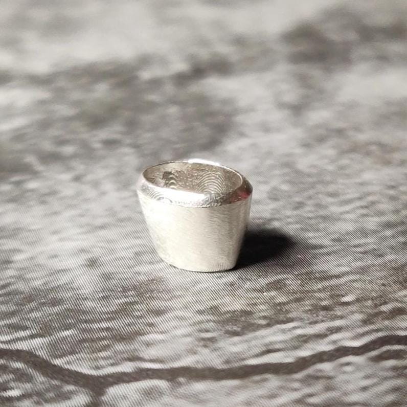 Upright 6x4mm oval silver bezel setting on a dark surface, showing the clean rim and inner seat for a gemstone.