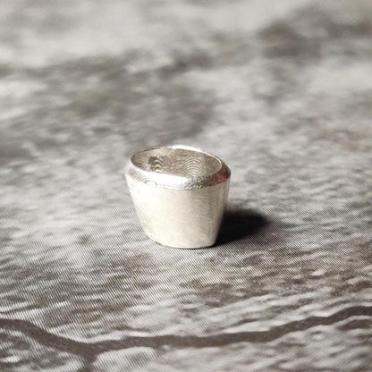 Upright 6x4mm oval silver bezel setting on a dark surface, showing the clean rim and inner seat for a gemstone.