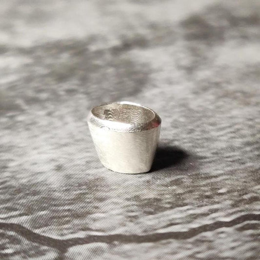 Upright 6x4mm oval silver bezel setting on a dark surface, showing the clean rim and inner seat for a gemstone.